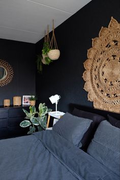 a bed room with a neatly made bed and two plant hangings on the wall