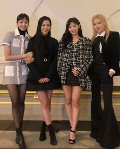 three women standing next to each other in front of a white wall wearing black and white outfits