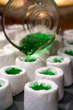 green liquid being poured onto marshmallows on a tray