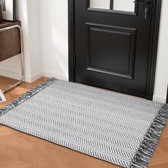 a black and white rug sitting on top of a wooden floor next to a door