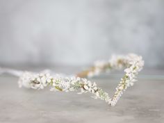 a white flowered headband is laying on a table with a gray wall in the background