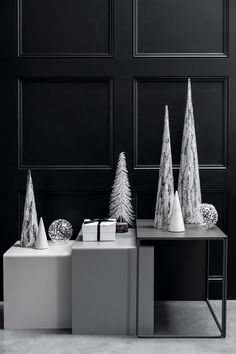 three white christmas trees sitting on top of a table next to boxes with presents in them