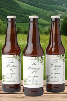 three bottles of beer sitting on top of a wooden table in front of a field