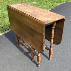 an old wooden desk sitting in the middle of a road next to a grassy area