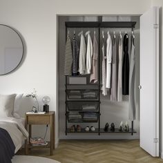 an open closet with clothes and shoes on the shelves, next to a bed in a bedroom