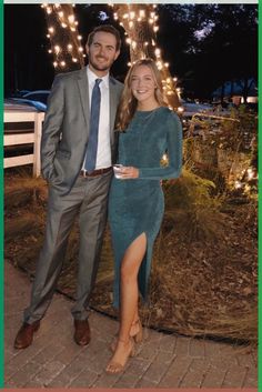 a man and woman standing next to each other in front of a string of lights