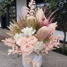 a vase filled with flowers and greenery on top of a table