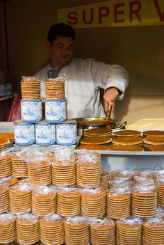 a man standing behind a counter filled with lots of cookies and pies on top of it