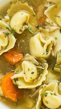 a white bowl filled with dumplings and carrots on top of a wooden table