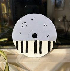 a white and black striped paper plate with musical notes on it's face, sitting on a window sill