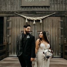 a bride and groom holding hands in front of an old building with roped doors