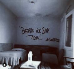 a room with graffiti written on the wall and two beds in it, one is made up