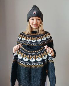 a woman wearing a black and white sweater with snowmen on it, standing in front of a gray background