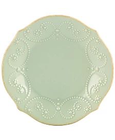 a green plate with white designs on the rim and bottom, sitting in front of a white background