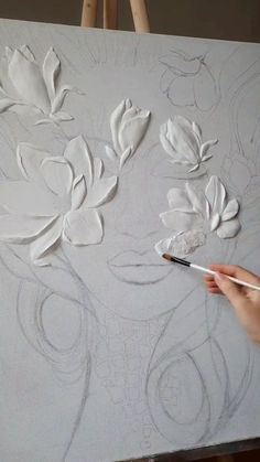 someone is drawing flowers on a canvas with a pencil and watercolors in front of them