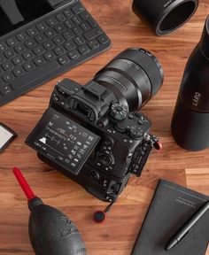 a camera sitting on top of a wooden table next to a laptop and other items