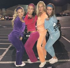 four women in matching outfits standing next to a car