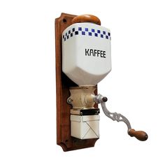 a keffe coffee maker mounted on a wall with a hook and wooden handle to hold it