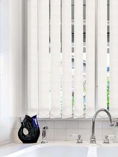 a white sink sitting under a window next to a faucet in a bathroom