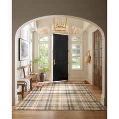 an archway leading into a living room with a rug on the floor and a black door