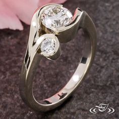 a close up of a ring with a flower in the background