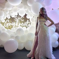 a woman standing in front of a backdrop with balloons