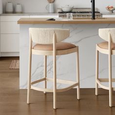 two wooden stools sitting in front of a counter with white marble and wood accents