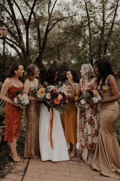 a group of women standing next to each other holding bouquets in their hands and laughing