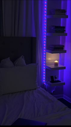 a bed with white sheets and purple lights on the headboard, next to a book shelf