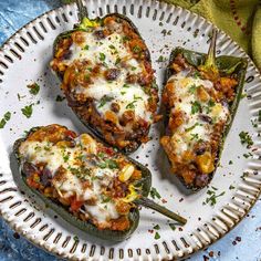 three stuffed peppers on a plate with cheese and seasoning sprinkled around them