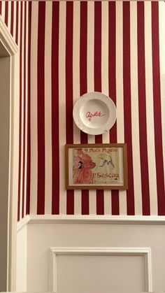 a red and white striped wall with a plate on it's head above the door