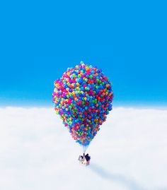 a person flying through the air on top of a balloon filled with colorful balls and streamers