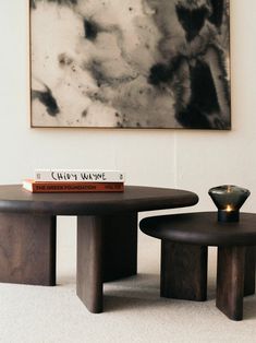 two tables with books on them in front of a painting