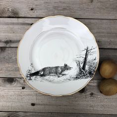 a plate with an image of a fox on it and two pears next to it