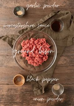 ingredients for ground beef in a glass bowl on a wooden table with spoons and measuring cups