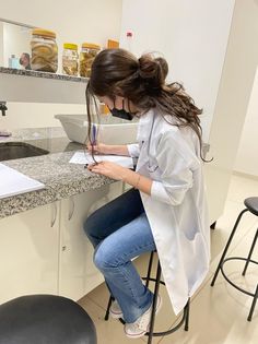 a woman sitting at a counter writing on a piece of paper