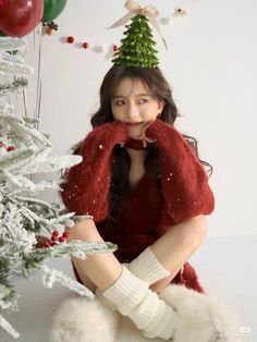 a woman sitting in front of a christmas tree