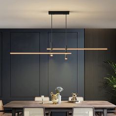 a dining room table and chairs with lights hanging from the ceiling above it, in front of black paneled walls