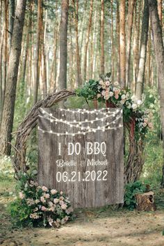 a wooden sign that says i do bbo surrounded by flowers and greenery in the woods