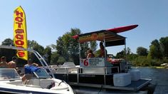 people are riding on the back of a boat with a canopy over it and a yellow sign that says hot dog