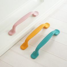 three different colored handles on a white counter