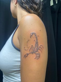 a woman's arm with a scorpion tattoo on the left side of her shoulder