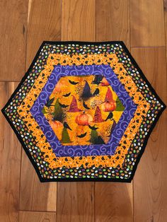 a patchwork table top with pumpkins and birds in the center on a wooden floor