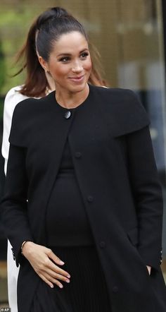 the pregnant woman is wearing a black coat