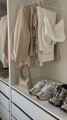 a closet with shoes and shirts hanging on the wall next to a white chest of drawers