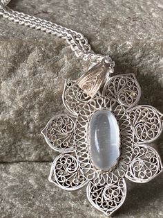 A pretty oval  Moonstone 11mm x6mm  set in an ornate filigree Silver Mount , beautiful delicate work , much better than normal in a heavier weight , total size 34mm  high including the filigree bale, 22mm wide, on a Silver  Curb Chain 45cm long White Oval Necklace With Intricate Design, Spiritual Oval Filigree Jewelry, Traditional Oval Cabochon Necklaces, Traditional Oval Cabochon Necklace, White Ornate Filigree Necklace, Ornate White Filigree Necklace, Ornate Oval Filigree Jewelry, Elegant Jewelry With Intricate Design And Oval Cabochon, Traditional Oval Filigree Necklaces