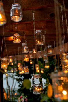 mason jars filled with water and lit candles are hanging from the ceiling in an indoor setting