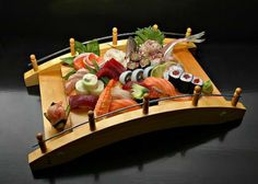 a wooden boat with sushi on it and chopsticks sticking out of the side