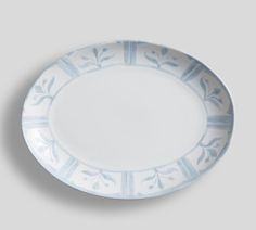 a white and blue plate with designs on it's rim, against a gray background