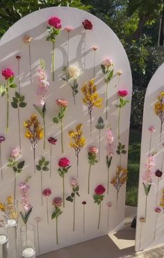 two white archs with flowers on them and candles in vases next to each other